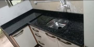 Bancada de granito preto com cuba e cooktop em cozinha com armários brancos
